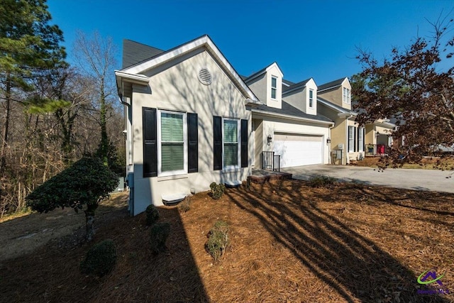 view of front of house featuring a garage, concrete driveway, and stucco siding