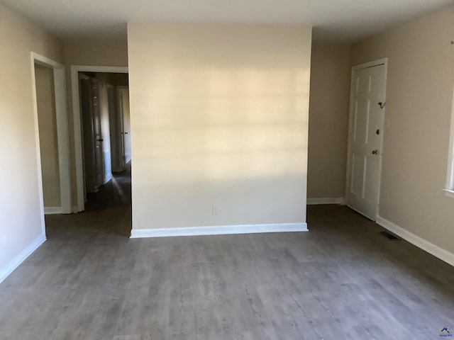 spare room featuring visible vents, baseboards, and wood finished floors