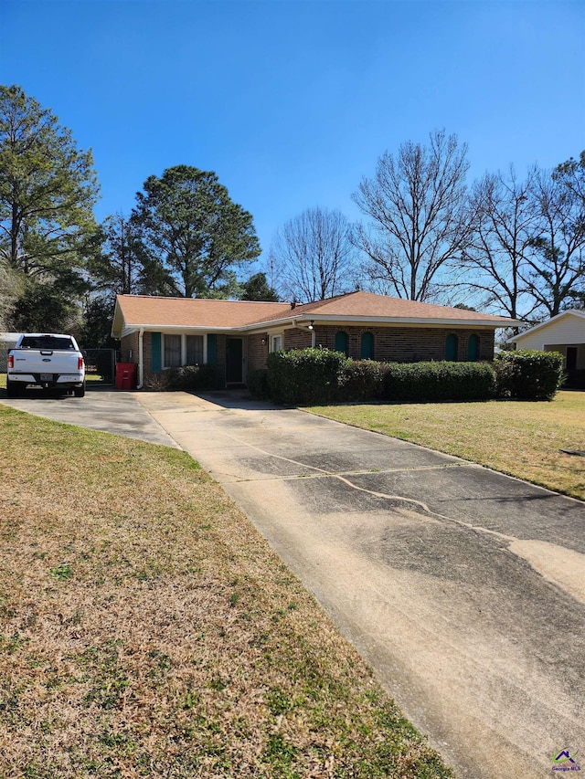 single story home featuring driveway, a front lawn, and brick siding