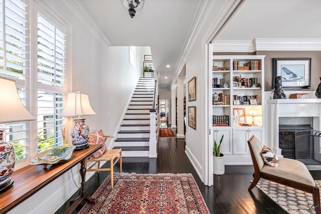 entrance foyer with a fireplace, baseboards, stairs, dark wood-style floors, and crown molding