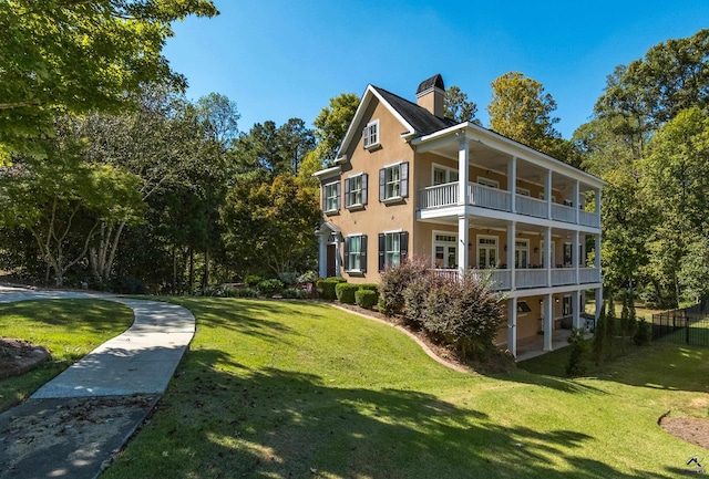 view of home's exterior with a balcony, a chimney, a lawn, and stucco siding