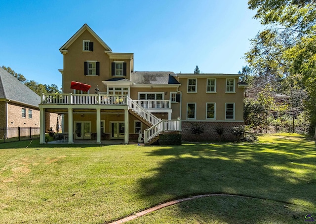 rear view of property featuring a deck, a yard, stairway, and fence