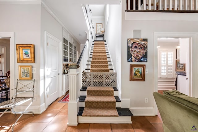 stairway with ornamental molding, baseboards, and tile patterned floors