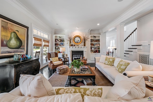 living room featuring built in shelves, a fireplace, ornamental molding, wood finished floors, and stairs