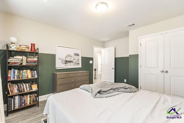 bedroom with a closet, visible vents, and light wood finished floors