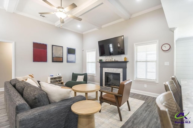 living room featuring visible vents, baseboards, a glass covered fireplace, beamed ceiling, and wood finished floors