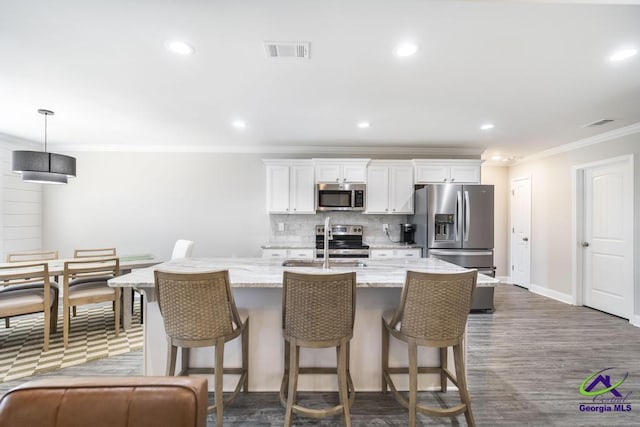 kitchen featuring tasteful backsplash, an island with sink, stainless steel appliances, a kitchen bar, and a sink