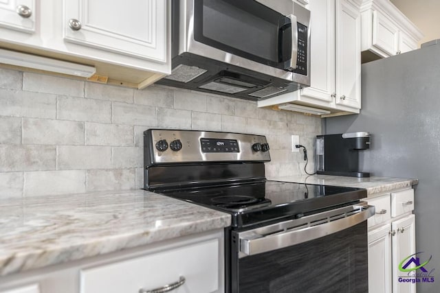 kitchen featuring white cabinets, tasteful backsplash, light stone counters, and stainless steel appliances