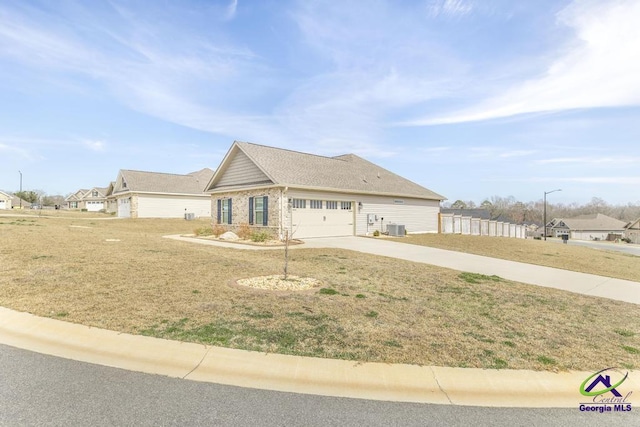 view of front of house featuring a front yard, concrete driveway, central AC, and an attached garage