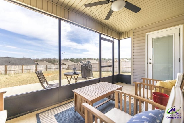 sunroom / solarium with a ceiling fan, wooden ceiling, and plenty of natural light