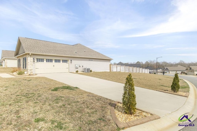 view of front of property with central AC unit, concrete driveway, an attached garage, fence, and a front lawn