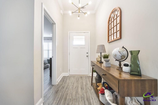 foyer entrance featuring a chandelier, ornamental molding, wood finished floors, and baseboards