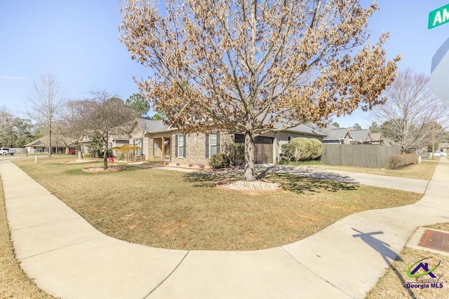 obstructed view of property with concrete driveway, an attached garage, fence, a front yard, and brick siding