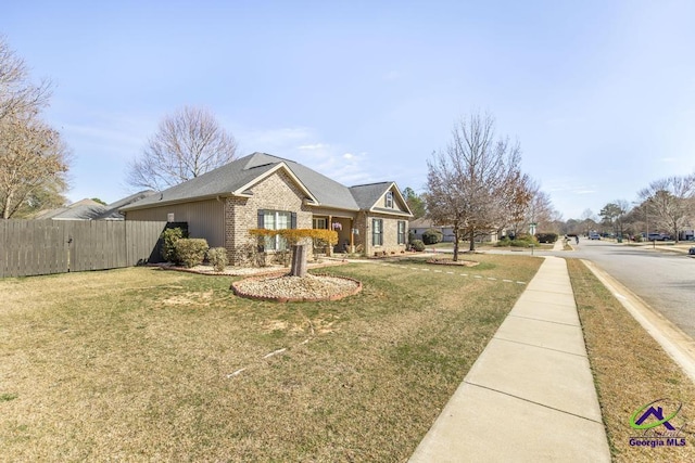 view of front facade featuring fence, a front lawn, and brick siding