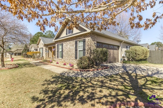 view of side of home with brick siding, a yard, fence, a garage, and driveway