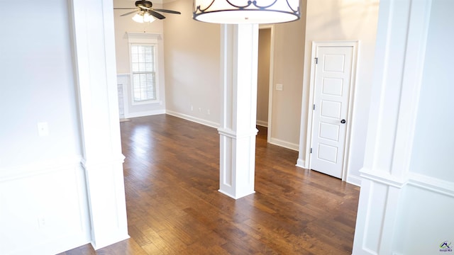 unfurnished dining area featuring ornate columns, baseboards, a ceiling fan, and dark wood-type flooring