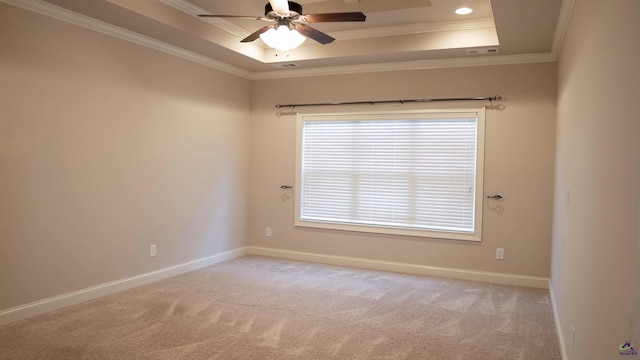 spare room featuring ornamental molding, a tray ceiling, light colored carpet, and baseboards