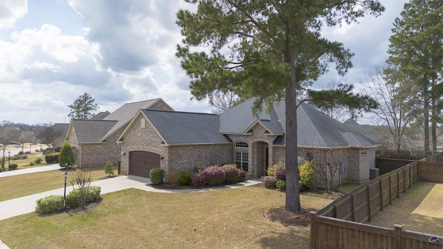 view of front facade with a garage, concrete driveway, fence, a front yard, and brick siding