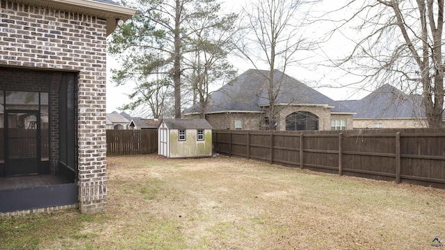 view of yard featuring a storage shed, a fenced backyard, and an outbuilding