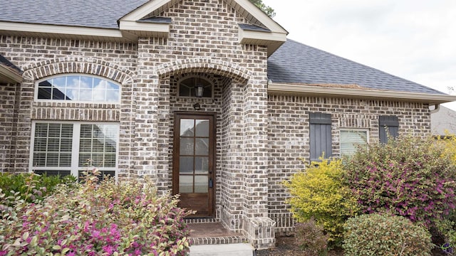 entrance to property with brick siding and roof with shingles