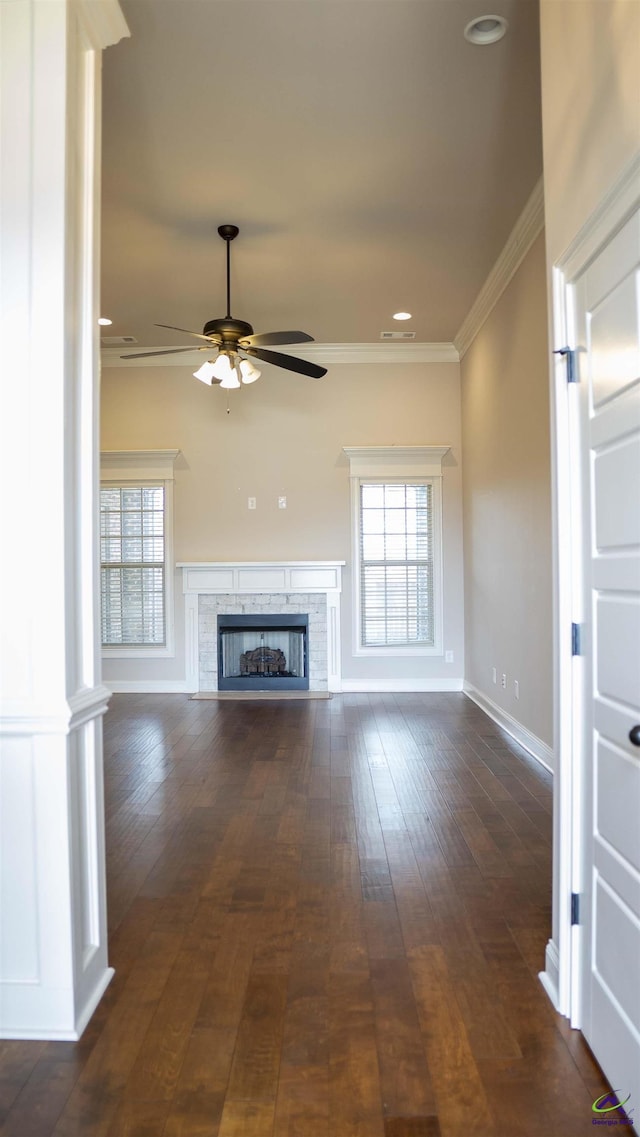 unfurnished living room featuring ornamental molding, a healthy amount of sunlight, a fireplace, and dark wood-style floors