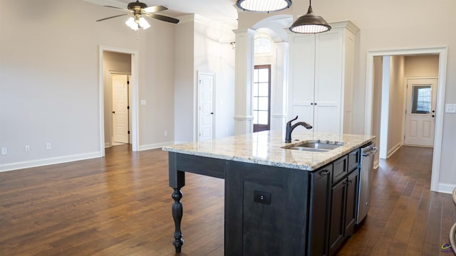 kitchen featuring dark wood-style floors, hanging light fixtures, stainless steel dishwasher, a sink, and ornate columns