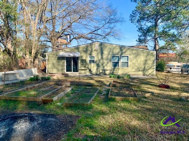 back of house with fence and a garden