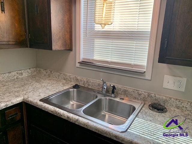 kitchen featuring light countertops, dark brown cabinets, and a sink