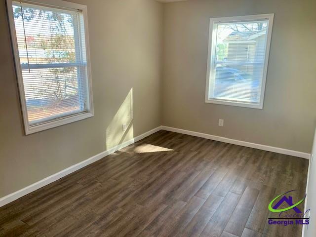 empty room with dark wood finished floors and baseboards