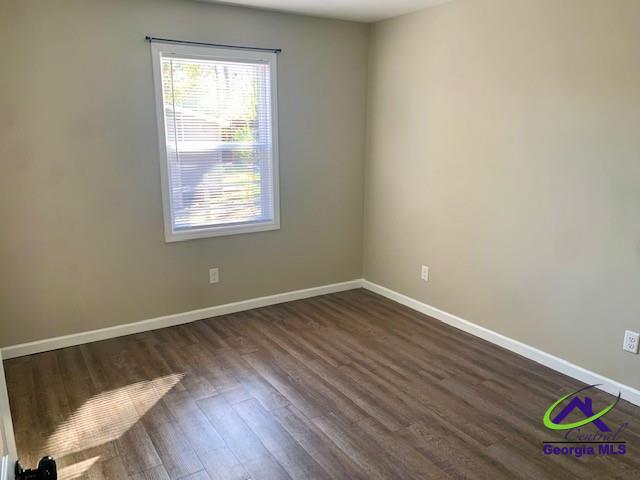empty room featuring dark wood finished floors and baseboards