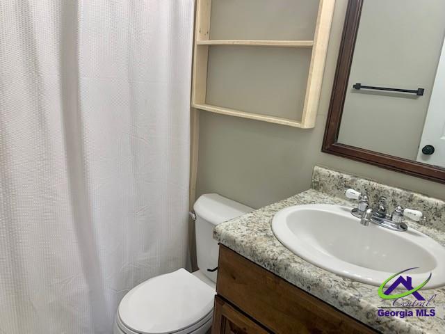 bathroom with a shower with shower curtain, vanity, and toilet