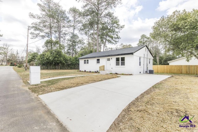 view of front of property featuring entry steps, central air condition unit, fence, stucco siding, and a front yard