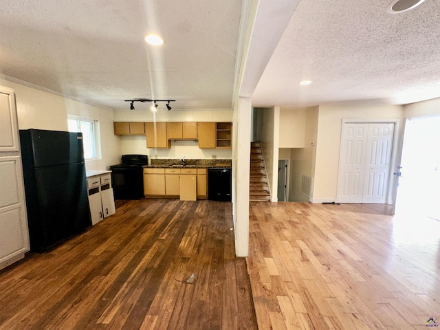 kitchen featuring a textured ceiling, black appliances, dark wood-type flooring, and a sink