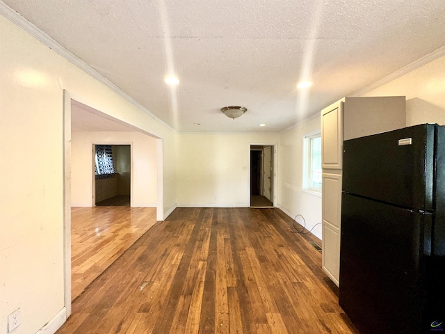 spare room with wood-type flooring, a textured ceiling, baseboards, and crown molding