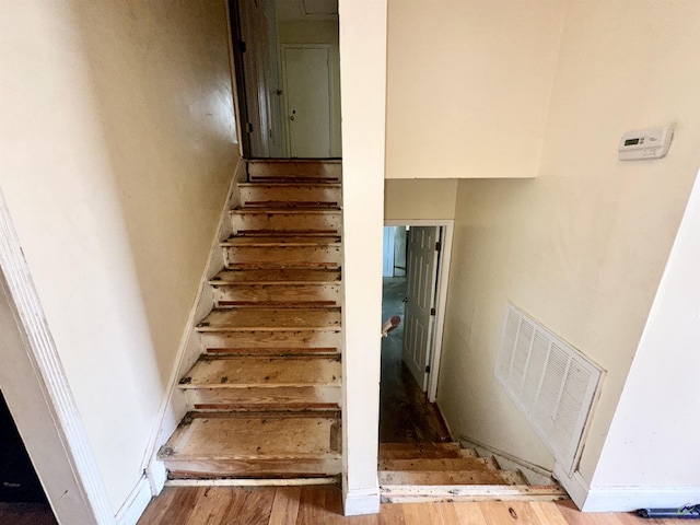 staircase with visible vents and wood finished floors