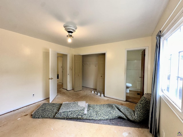 bedroom featuring ensuite bathroom, multiple windows, a closet, and baseboards