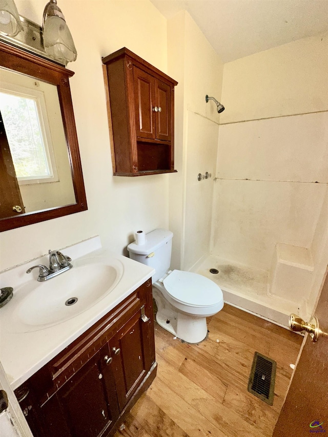 bathroom featuring visible vents, toilet, vanity, wood finished floors, and walk in shower