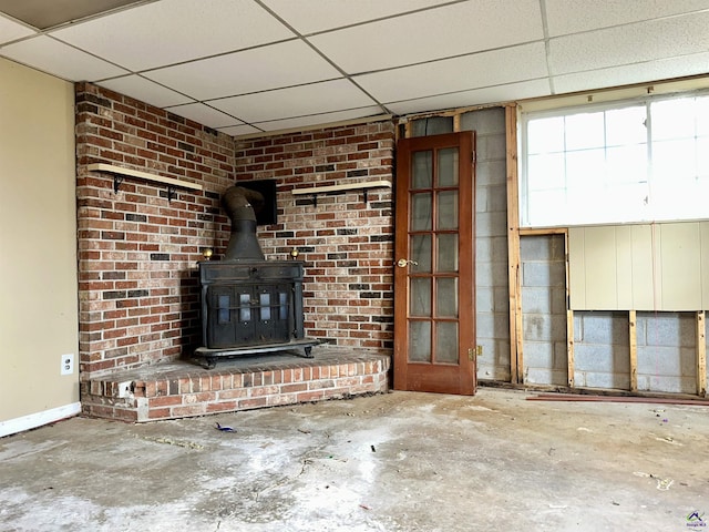 unfurnished living room with a wood stove, concrete floors, and a paneled ceiling