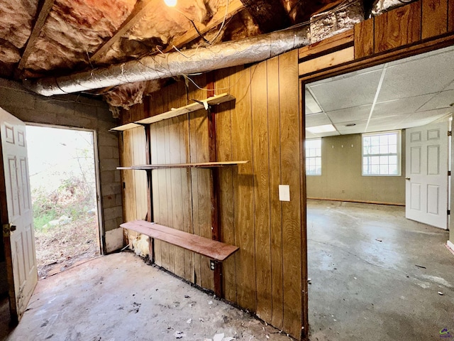 interior space with a drop ceiling and unfinished concrete flooring