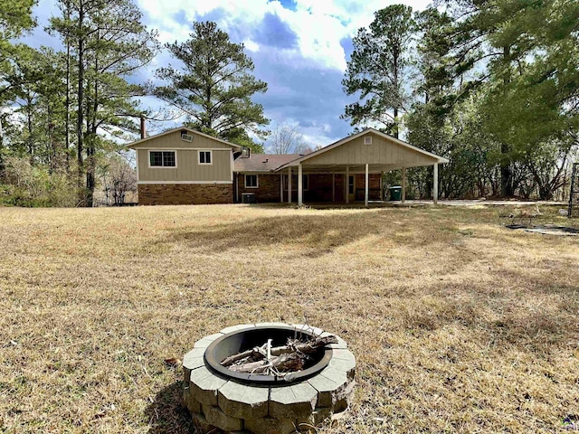 view of front facade with a fire pit, brick siding, and a front yard