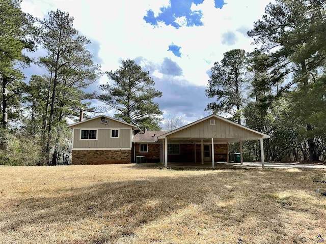 back of property featuring a carport, cooling unit, and a yard