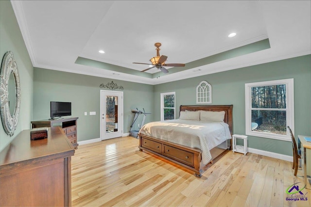 bedroom featuring a raised ceiling, light wood-style flooring, and baseboards