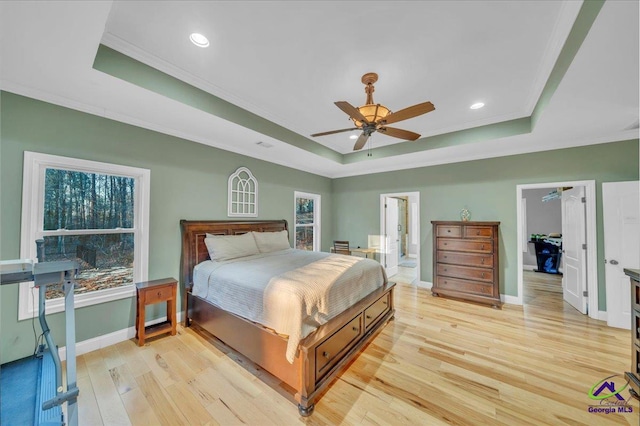 bedroom with light wood finished floors, baseboards, ornamental molding, and a raised ceiling