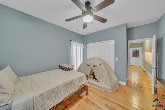 bedroom featuring a ceiling fan, light wood-type flooring, a closet, and baseboards