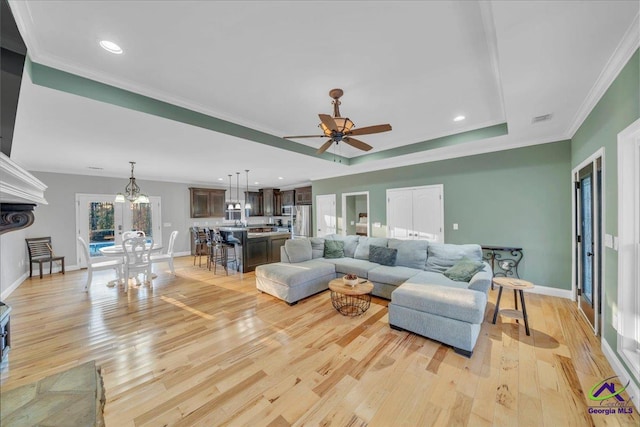 living room featuring visible vents, crown molding, light wood-style flooring, and baseboards