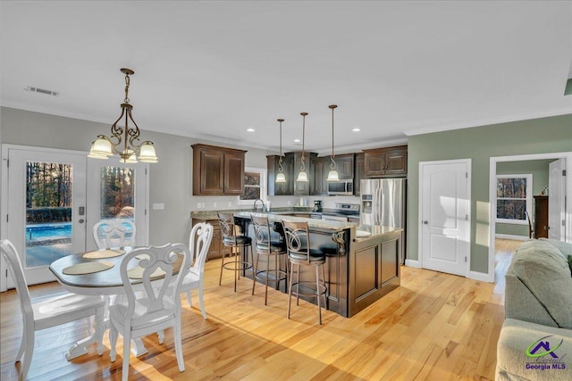 kitchen featuring stainless steel appliances, crown molding, dark brown cabinetry, and light wood finished floors