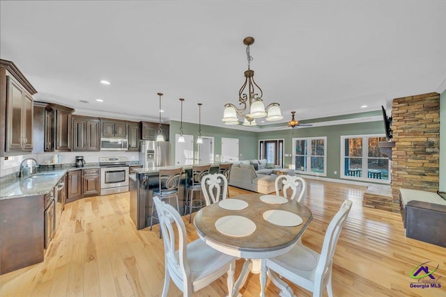 dining area with recessed lighting, light wood-style flooring, baseboards, and ceiling fan with notable chandelier