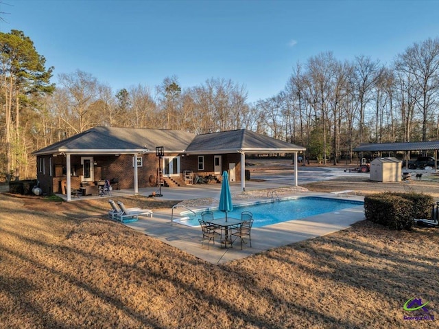 pool with a patio area, an outdoor structure, a lawn, and a shed