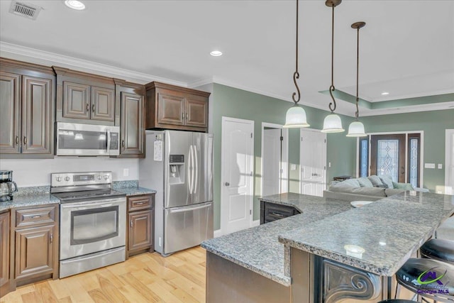 kitchen featuring stainless steel appliances, visible vents, a kitchen breakfast bar, light wood-type flooring, and a center island