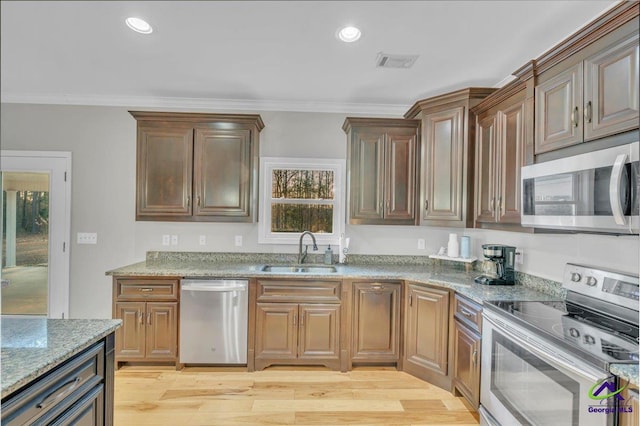 kitchen with appliances with stainless steel finishes, visible vents, a sink, and crown molding